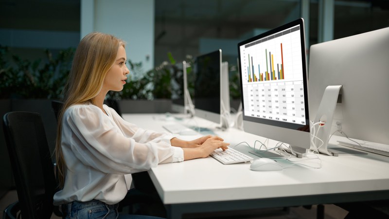 Junge Frau erstellt Balkendiagramme am Computer