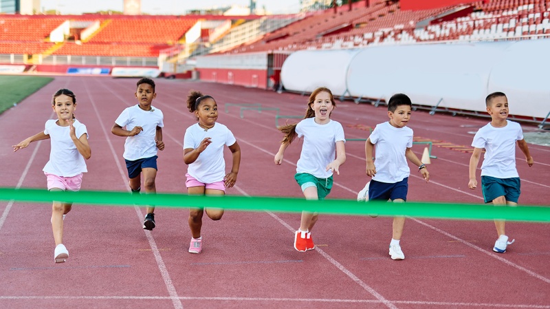 Mädchen und Jungen rennen auf einer Rennbahn