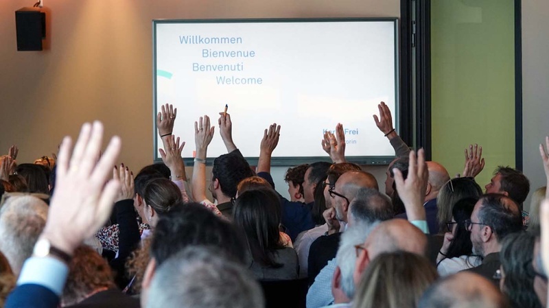 Foto aus der Konferenz: Teilnehmende heben die Hand in die Höhe