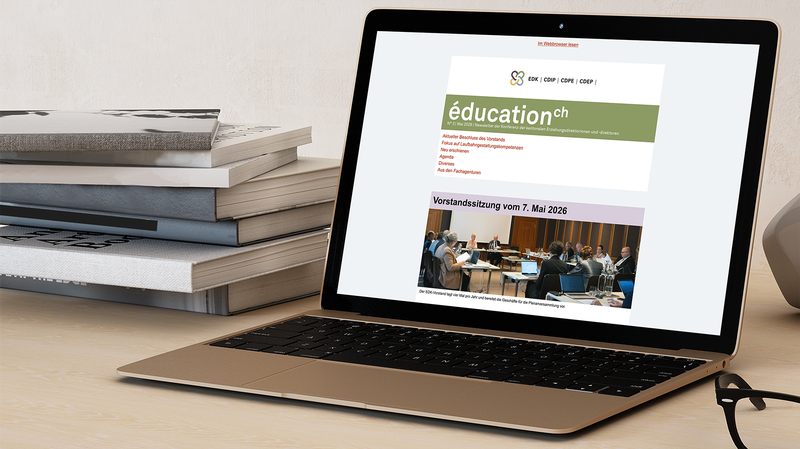 Laptop mit Ansicht EDK Newsletter und einem Bücherstapel links im Bild