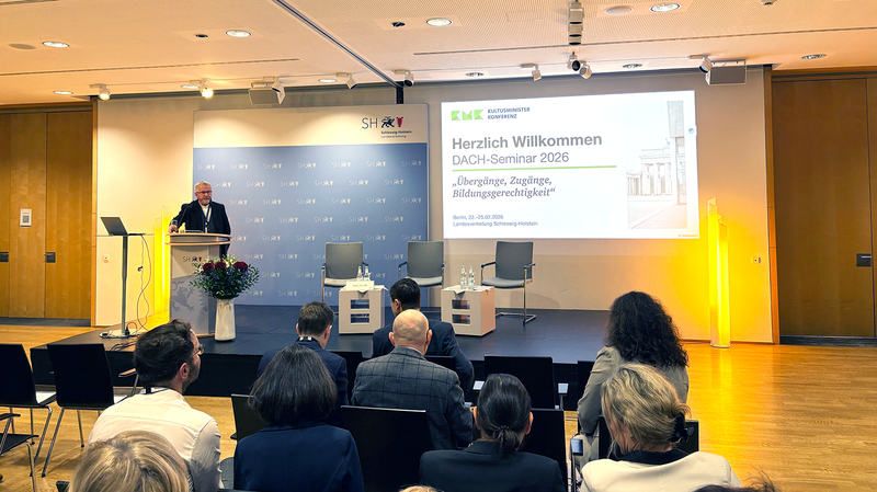 Foto vom DACH-Seminar, Udo Michalik steht auf der Bühne und begrüsst alle