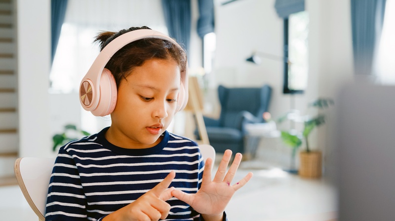 Un enfant porte des écouteurs et écoute quelque chose.